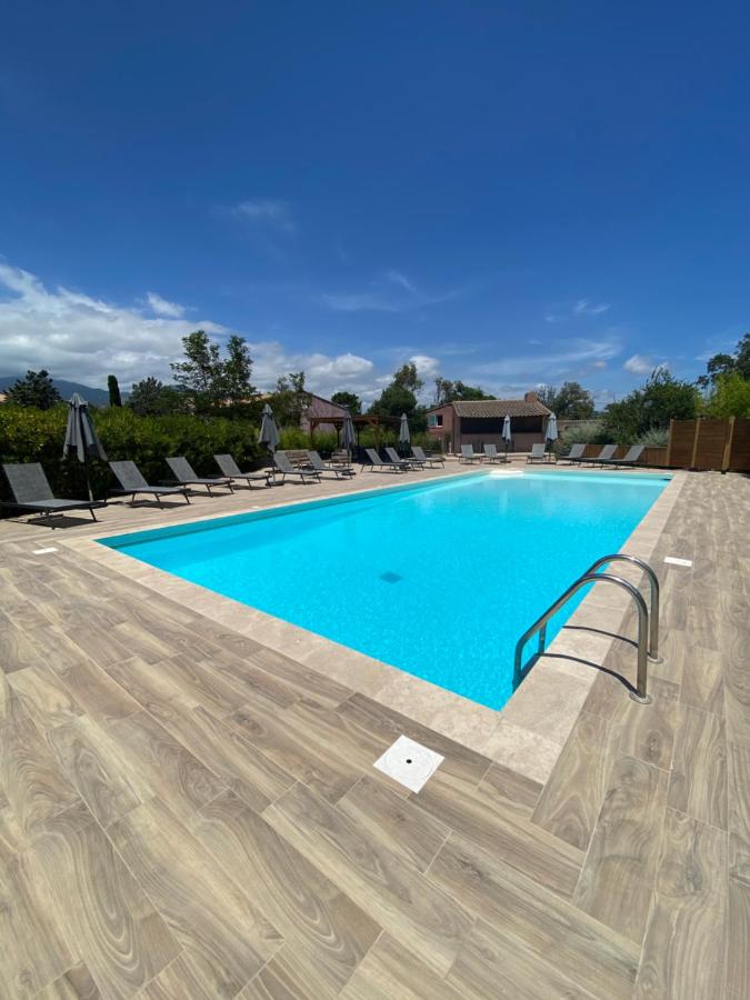 Piscine extérieure avec transats sous ciel bleu.