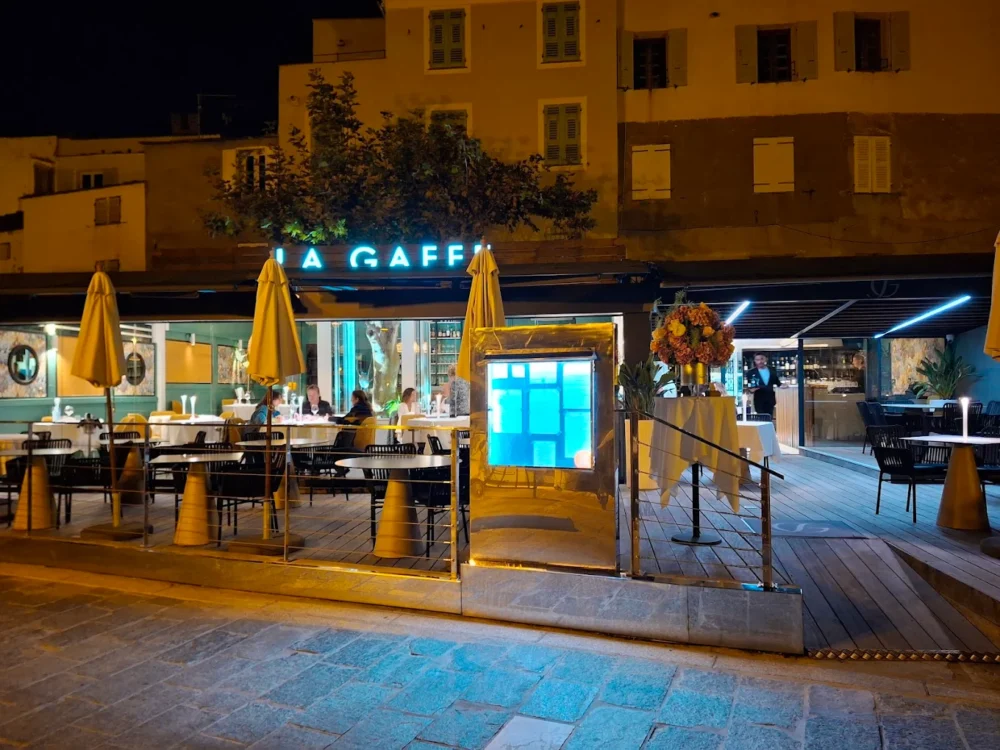 Restaurant terrasse éclairé la nuit avec parasols.