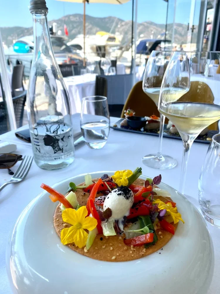 Plat gastronomique avec fleurs et verrerie en extérieur.