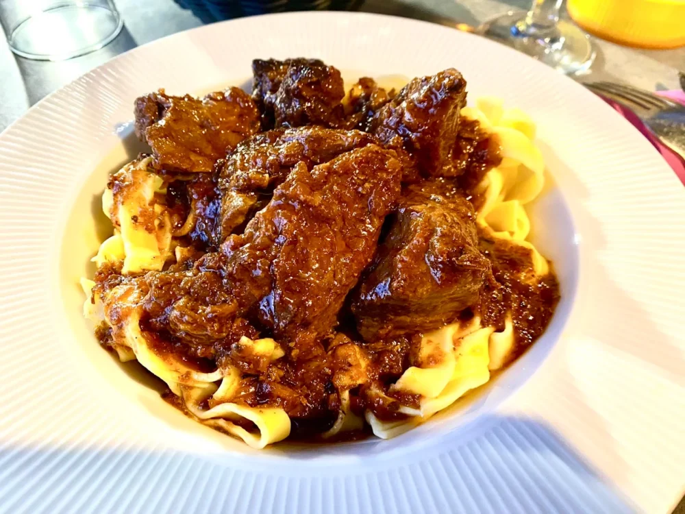 Plat de pâtes avec viande en sauce brune.