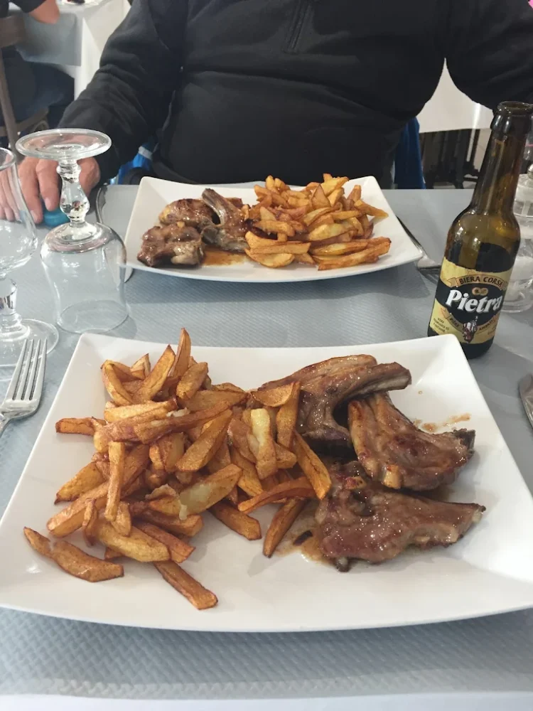Assiettes de frites et viande grillée, bière en bouteille.