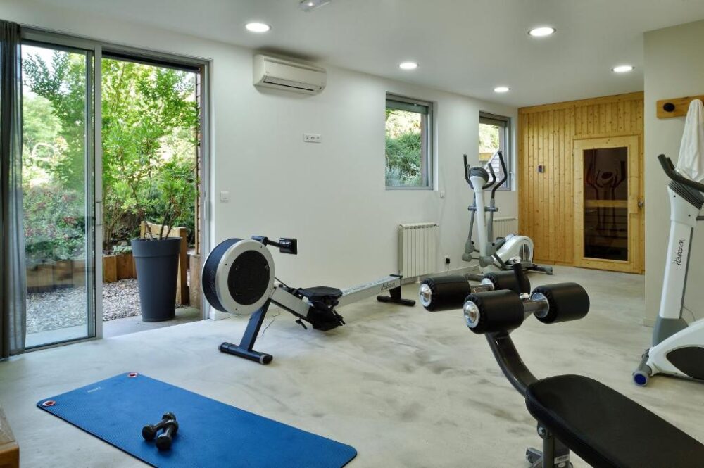 Salle de sport moderne avec équipements et lumière naturelle.