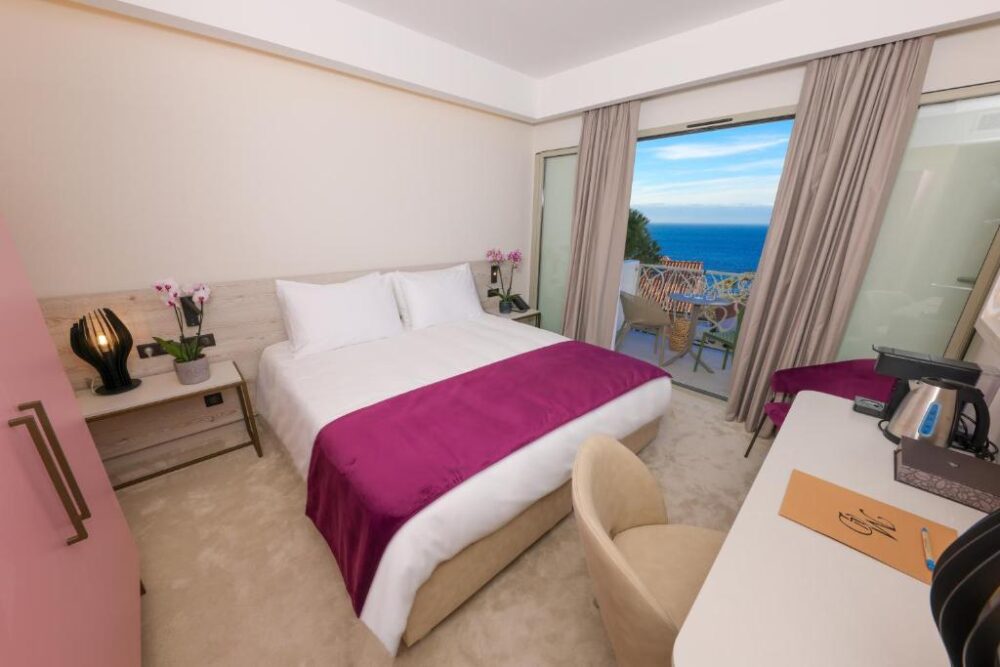 Chambre d'hôtel avec vue sur mer depuis balcon.