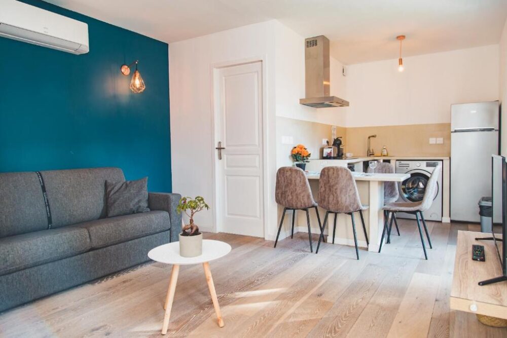 Salon moderne avec cuisine ouverte, canapé et table.