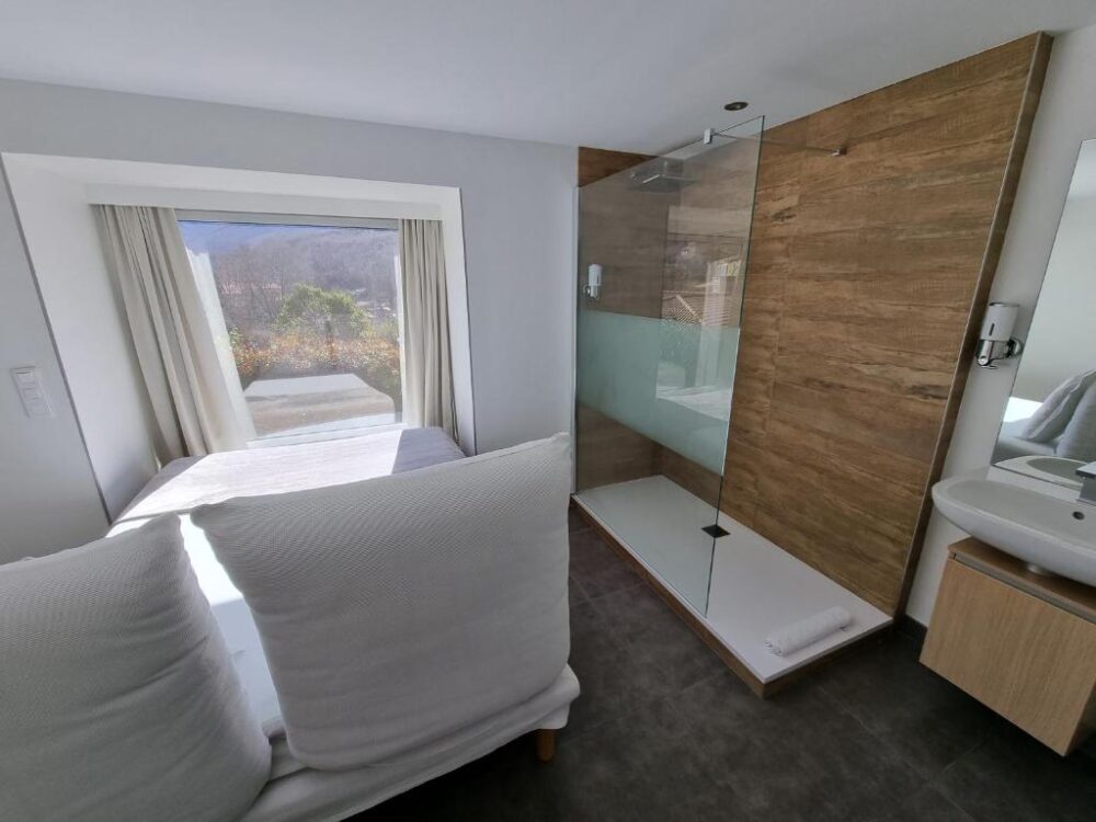 Chambre lumineuse avec douche en verre et vue.