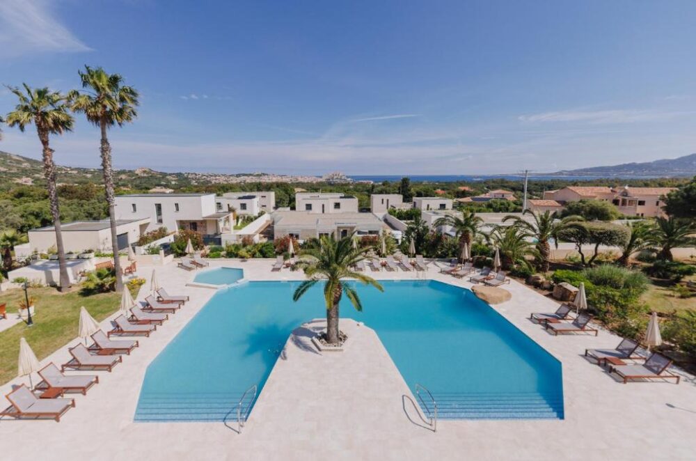 Piscine extérieure avec transats et palmiers.