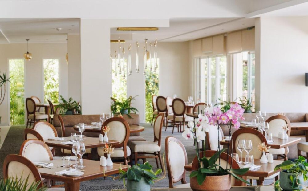 Salle de restaurant chic et lumineuse, orchidées présentes.