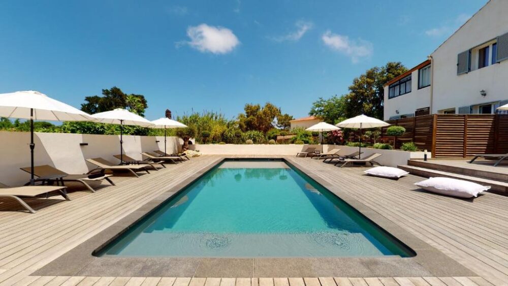 Piscine extérieure avec chaises longues et parasols.